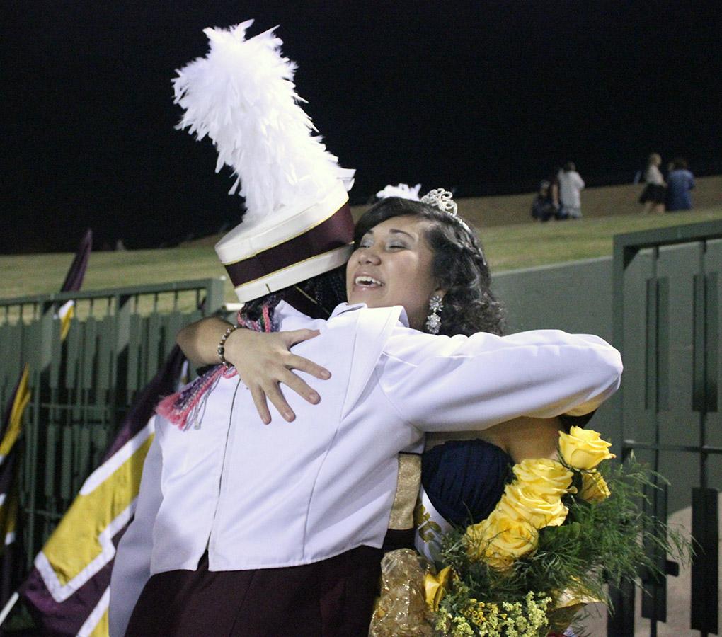 Sabina Marroquin, history education senior, hugs her bandmates as they congratualte her on being Midwestern State University's 2014 Homecoming Queen, Saturday at Memorial Stadium. Elijah Mire, senior, won 2014 Homecoming King. Photo by Rachel Johnson