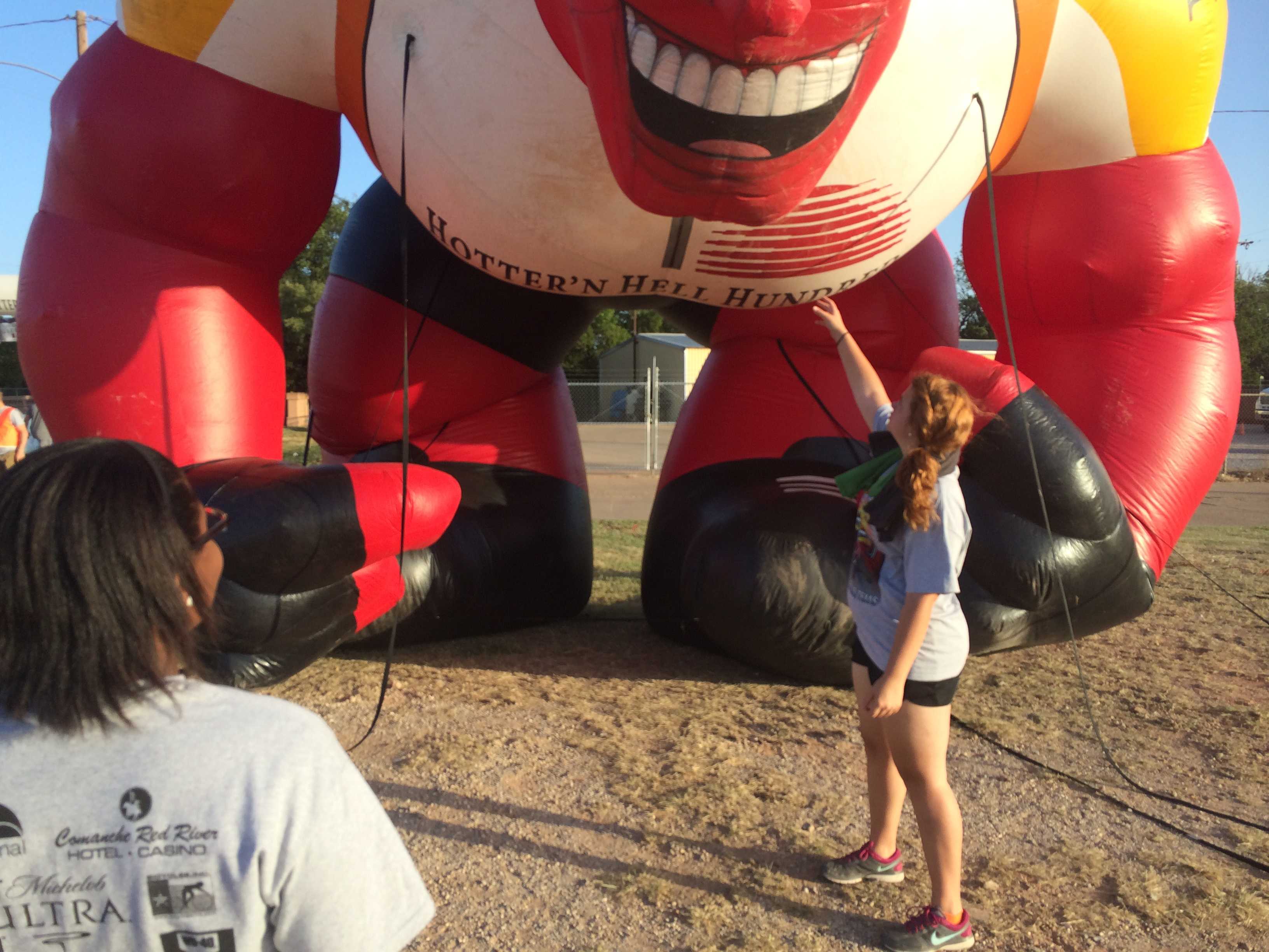 Talia Harris, mass communication sophomore, and Macy Pritchett, education sophomore, prepare to pack up and move "Pyro Pete" as volunteers begin deflating Hotter 'n Hell's unofficial mascot. Photo by Ethan Metcalf