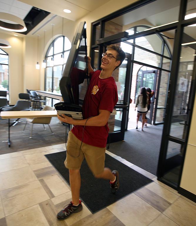 Tanner Conley, business sophomore, moves a television for a resident during Move-in for Legacy Hall at Midwestern State University, Aug. 20, 2016. Photo by Bradley Wilson