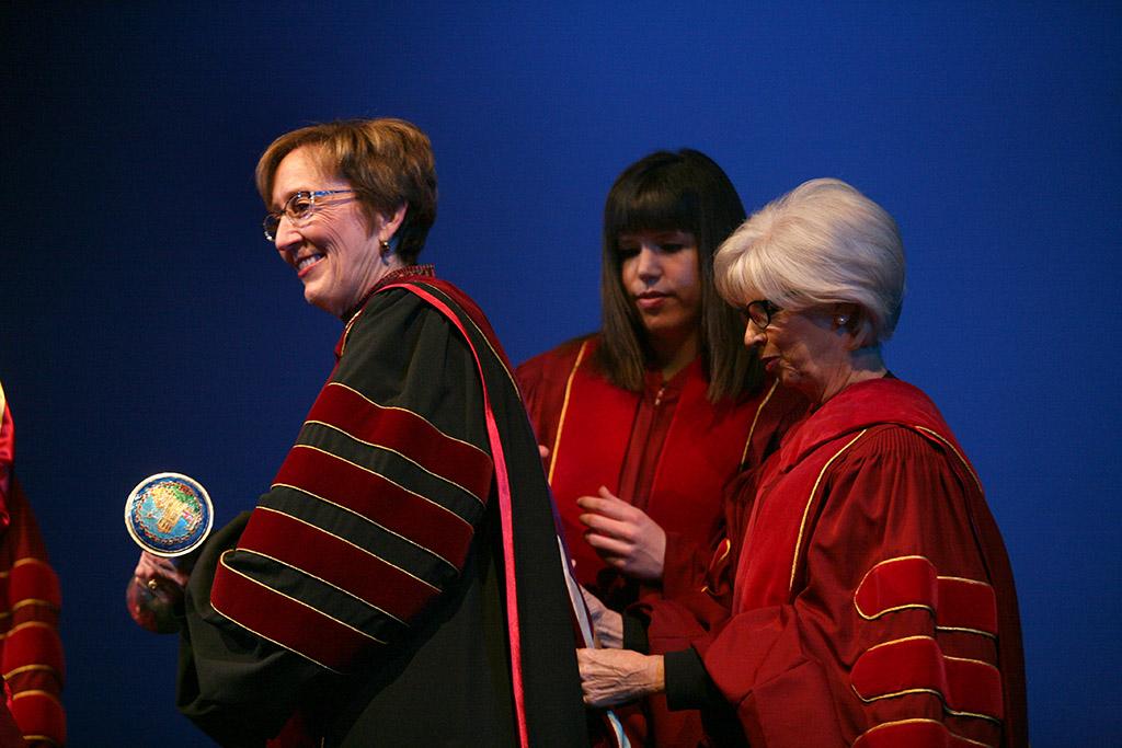 Megan Piehler and Nancy Marks, members of the Board of Regents, put the ceremonial hood on Suzanne Shipley, university president, Midwestern State University, Dec. 11, 2015. Photo by Bradley Wilson