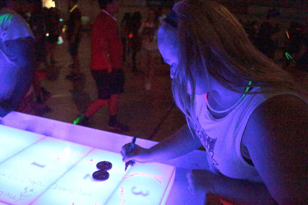Emily Burns, theatre freshman, drawing on the shuffleboard table at the GloCade in the DL Ligon Coliseum on Aug 24. Photo by Kayla White.