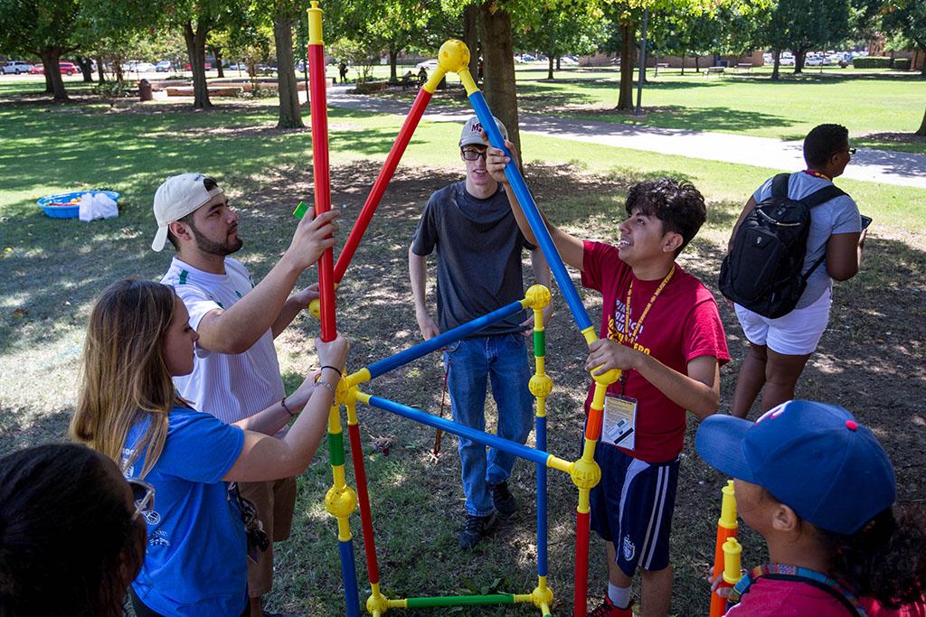 With friends on the orange team, Orlando Espinoza, psychology freshman, builds a structure on the Quad as part of Roundup Olympics. Photo by Izziel Latour