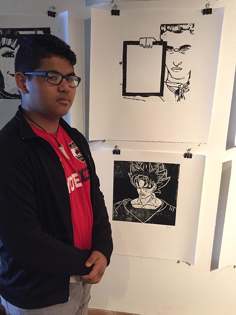 Nevin Diaz, freshman at Wichita Falls High School, posing in front of his print (bottom) in the foyer of Fain Fine Arts, Feb.9. Photo by Conner Wolf.