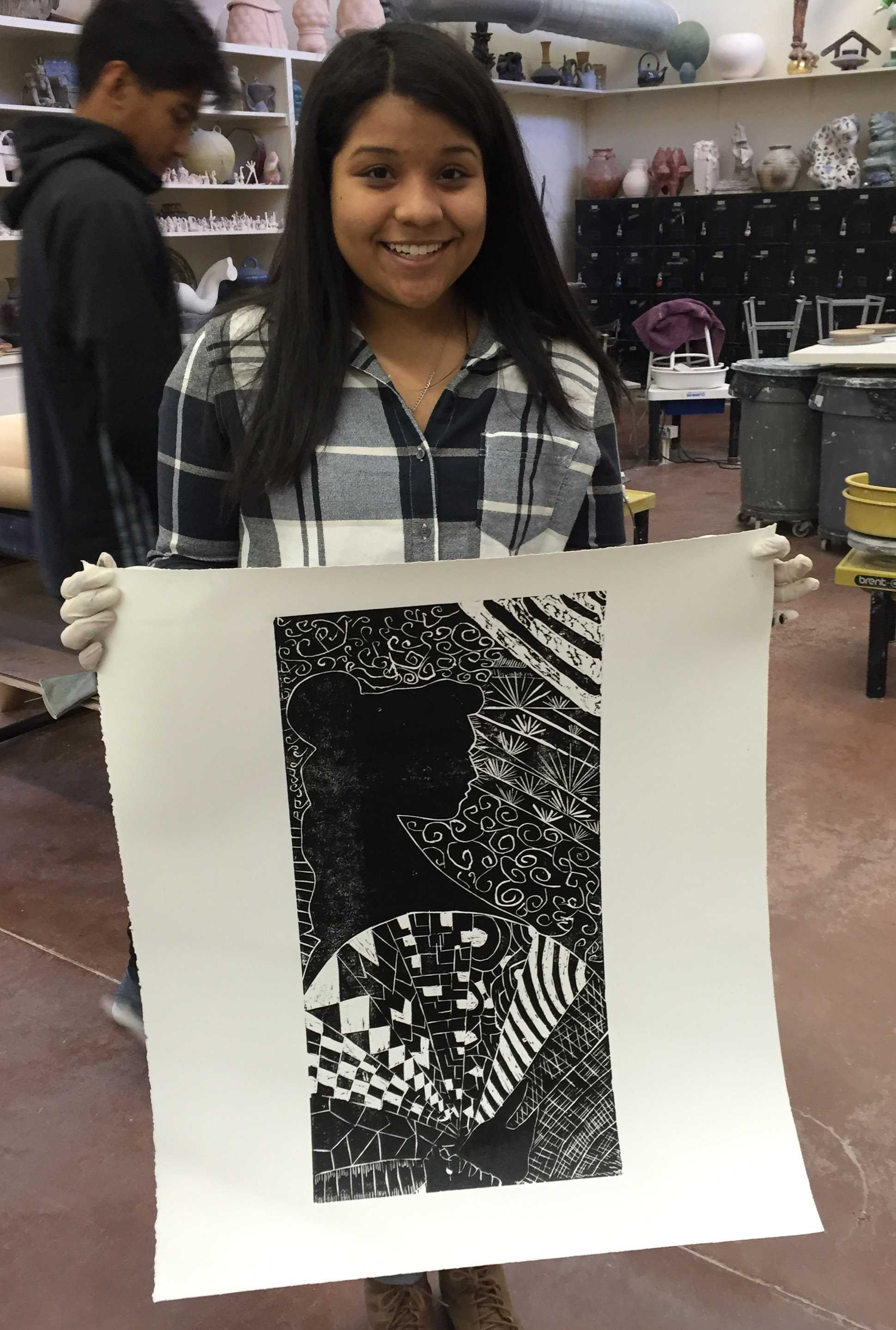Gabriela Nunez, junior at Hirschi High School, poses with her print, Patterns of the Wind, after pulling it up after getting rolled over to hang in the foyer of Fain Fine Arts, Feb. 9. Photo by Conner Wolf.