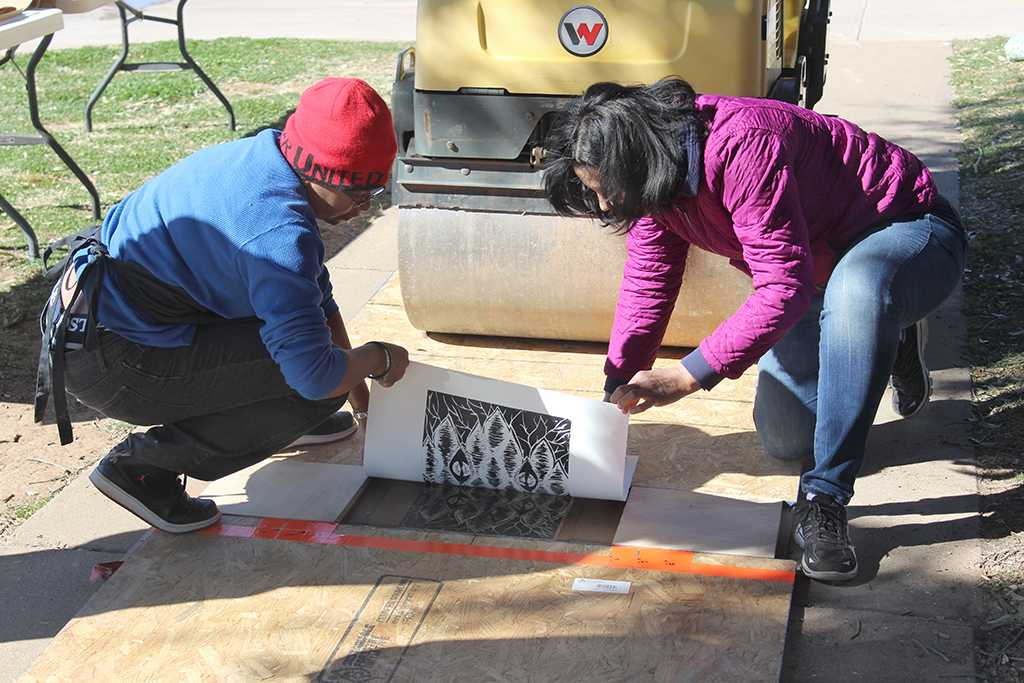 Lizca Bass, painting senior, and Auria Sanchez, teaching certification senior, unpeel the paper from the wood block to reveal the image for the Steamroller Print Event on Nocona Trial set up as a collaboration between MSU's Harvey School of Visual Arts and Wichita Falls Independent School District high schools, Feb 9, 2016. Photo by Francisco Martinez