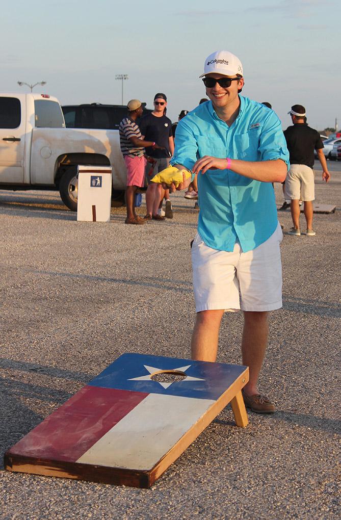 Caleb Pylant, biology junior, plays a game of bean bag toss set up by Sigma Alpha Epsilon in the new designated tailgating section of the parking lot outside of Memorial Stadium, Saturday Sept. 5, 2015. Midwestern State beat Truman State 31-3 in their opening game of the season. Photo by Rachel Johnson