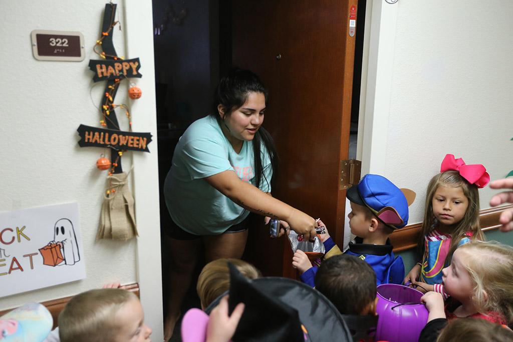 Clarissa Rios, dental hygiene freshman, passes out candy while the kids of YMCA trick or treat in Killingsworth Residence Hall at Midwestern State University. Photo by Justin Marquart