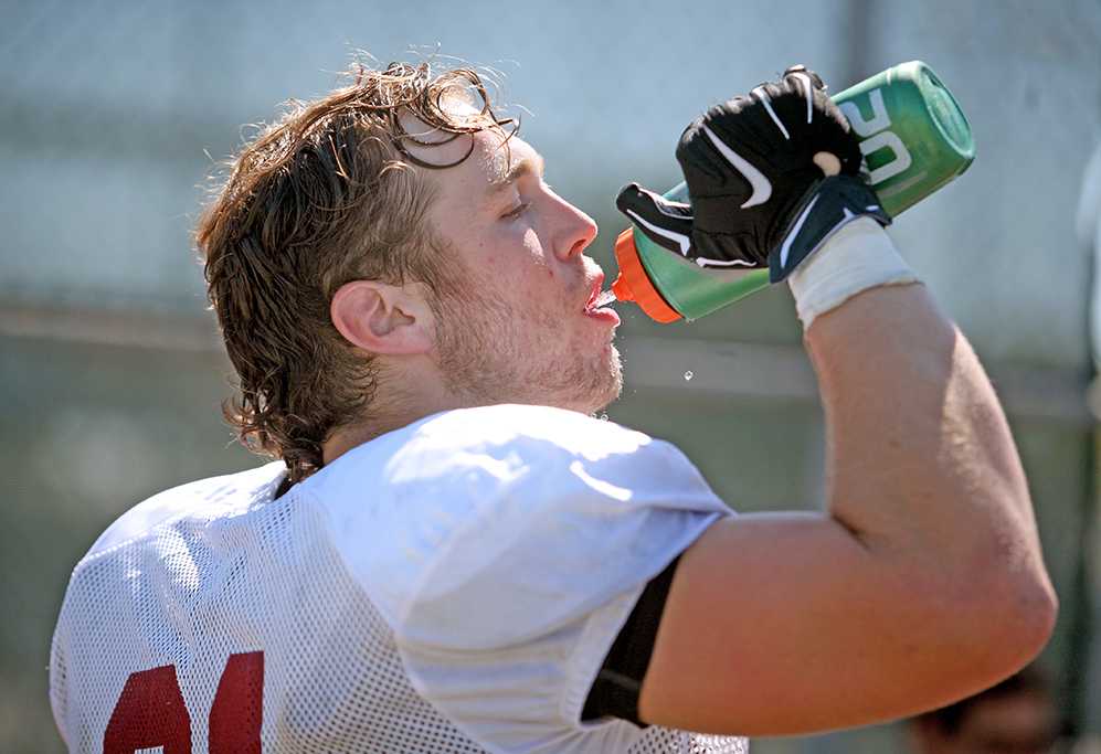 Blaine Albrecht, tight end, drinks water in between drills during two-a-day practice on Aug. 16. Albrecht said, "The turf is definitely hotter, but it has a more game like feel." Photo by Bradley Wilson.