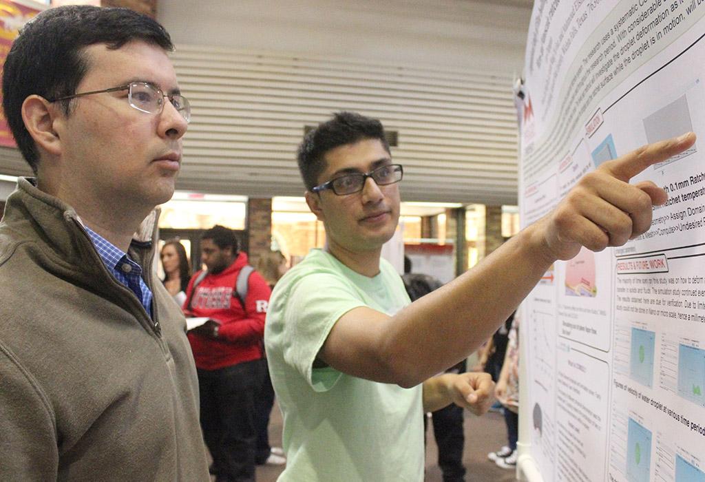 Kiran Chapagain, mechanical engineer junior, presents his poster on "Computational Study of Film Boiling Droplet Motion on Micro- and Nanoscale Ratchets" to eduardo Colmenares, professor of computer science and one of the judges, at the Undergraduate Research and Creative Activity Forum, held in the CSC Atrium, Nov. 19. Photo by Rachel Johnson