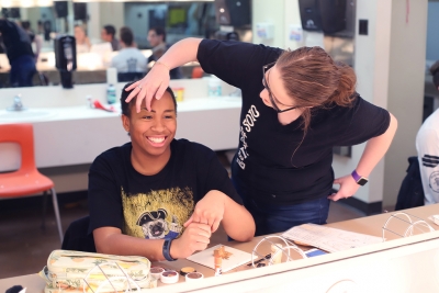 Abby Allen, theater education sophomore, helps Nicole Smalls, Penelope Pennywise and theater performance sophomore, draw on her eyebrows for Urinetown in the dressing room on Friday, Feb. 16, 2018. Photo by Sarah Graves
