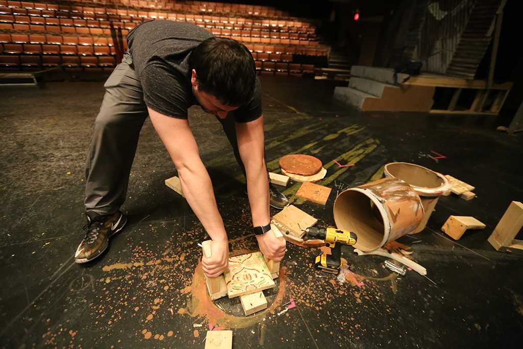 Ben Ashton helps to destroy some of the set plumbing while taking down the set of "Urinetown." Photo by Bradley Wilson