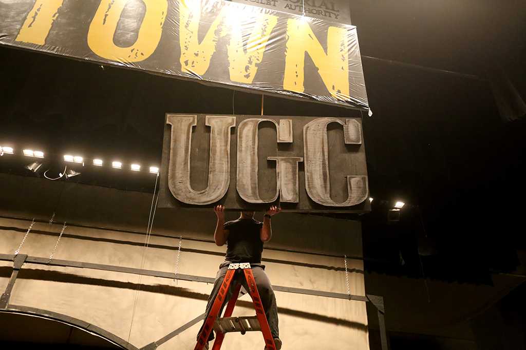 Ben Ashton helps to take down one of the signs while other crew members take down the set of "Urinetown." Photo by Bradley Wilson