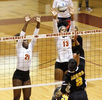 Raven Presley, mechanical engineering freshman, and Aerielle Edwards, applied arts & aciences senior, jump up to block the incoming ball from a Cameron University opponent during the volleyball game in D.L. Ligon Coliseum on Nov. 9, 2017. Photo by Harlie David