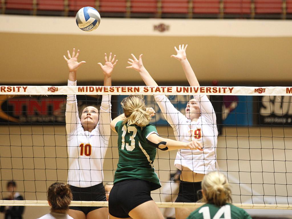 Kendall Chamberlain, nursing freshman, and Olivia Schiffner, excersize physiology freshman, go up to block a spike from an Eastern New Mexico Univeristy player during the game held in D.L. Ligon Coliseum, Oct. 27.  MSU lost to ENMU 1-3. Photo by Rachel Johnson