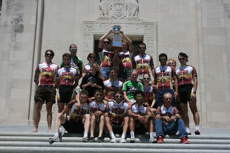 The cycling team proudly lifts its fourth consecutive conference trophy.  Photo by Loren Eggenschwiler