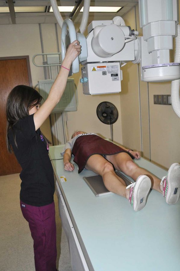 Radiology major, Heather Owens a junior, prepares to bring down the x-ray tube to take x-rays of Janel Campbells knee, a junior with a major in Nursing.