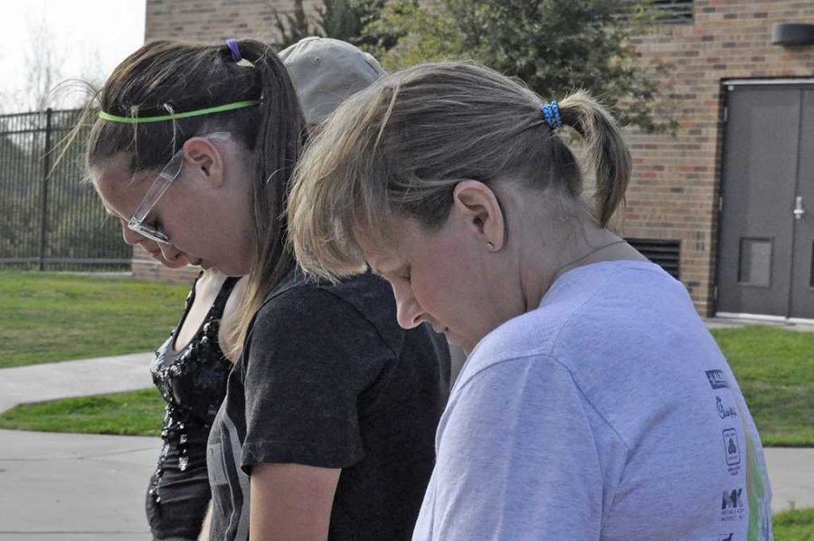 Kim Ferris prays for the victims and their families Tuesday before they walk around Sikes Lake.