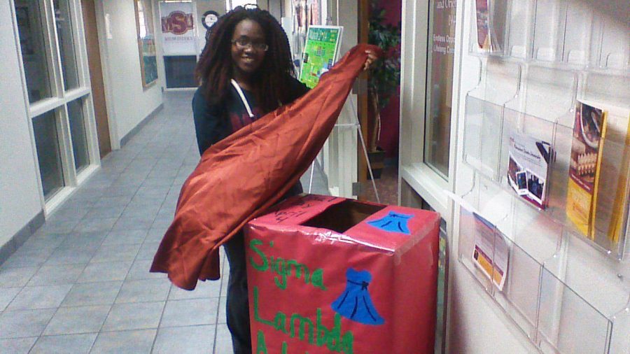 President of Sigma Lambda Alpha sorority Natalie Nduku stands beside a donation box outside of the student development office holding a dress that was donated for neglected and abused children.  Photo by Mandi Elrod