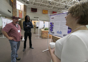 Beth Veale´, director of interdisciplinary education, and Charles Watson, biology assistant professor, listen to Gamal Frencis, senior in biology, explain his research, at the EURECA Poster Presentations in the Clark Student Center Atrium. Photo by Lauren Roberts