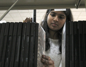 Pragna Vemuri, computer science graduate student, returns materials to the shelfs behind the front desk in Moffett Library Tuesday. Vemuri just started working in the libaray this semester. "It's peaceful working here and I'm able to study," Vemuri said. Photo by Lauren Roberts