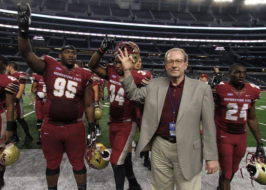 University President Jesse Rogers gestures with the football players during the playing of the school song after the Midwestern State University v. Eastern New Mexico game at AT&T Cowboys Stadium in Arlington, Sept. 20, 2014. Photo by Lauren Roberts
