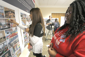 Alexis Carrizales, pharmacy freshman, and Keona Rollerson, computer science freshman, use a round blue sticker to choose the type of setting they would like in the community area of the new dorm. Students met with the Treanor Architects at the new housing meeting in Kiowa Wednesday. Deb Ebersole, partner at Studio D, said having students use color-coded stickers helps to track what qualities they want in the dorms. Students could choose from interior, exterior, community spaces, etc. Ebersole said, "Patterns will emerge with some of the same photos chosen." Photos with the most stickers on them were ones that had big windows, were modern, flexible and had open spaces. Photos by Lauren Roberts