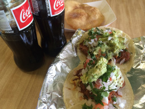 Pork street tacos with red chile sauce, guacamole, tomatoes, onions and cilantro. Mexican-bottled Coke and sopapillas. 