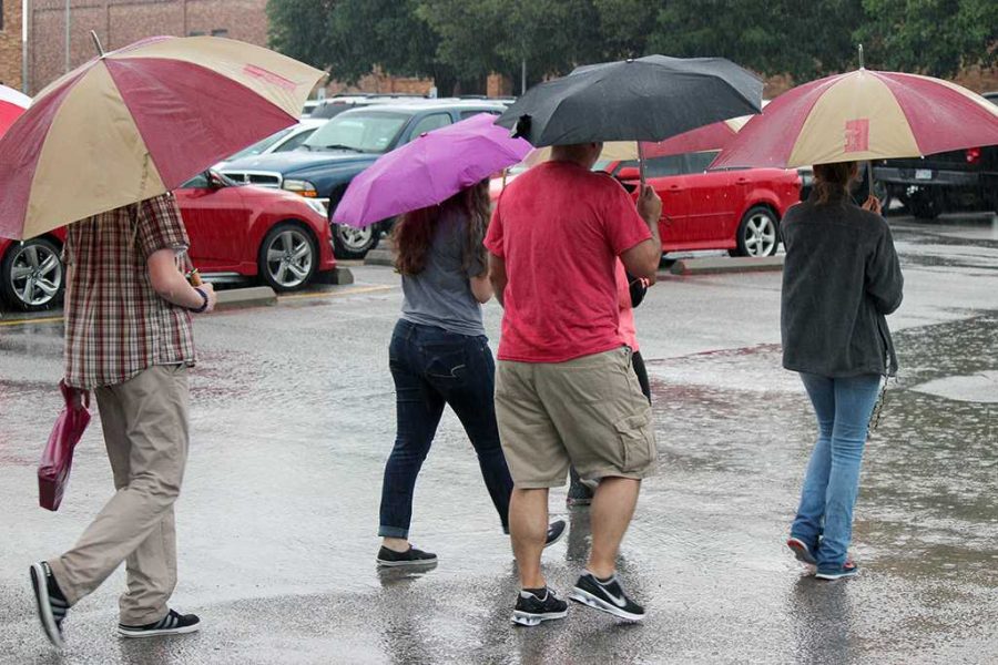 A group of people, near Fain Fine Arts, visiting campus are given a tour even though its pouring rain, and parts of campus are flooded. Photo by Francisco Martinez.