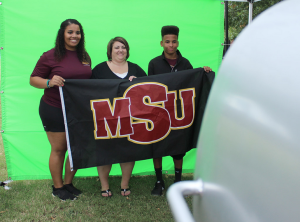Sierra Jones, athletic training senior, Shana Hancock, mother of Sierra, and Devin Hancock, Sierra's brother, get their picture taken at one of the booths in the Quad put up for Family Day, Sept. 26. Photo by Rachel Johnson