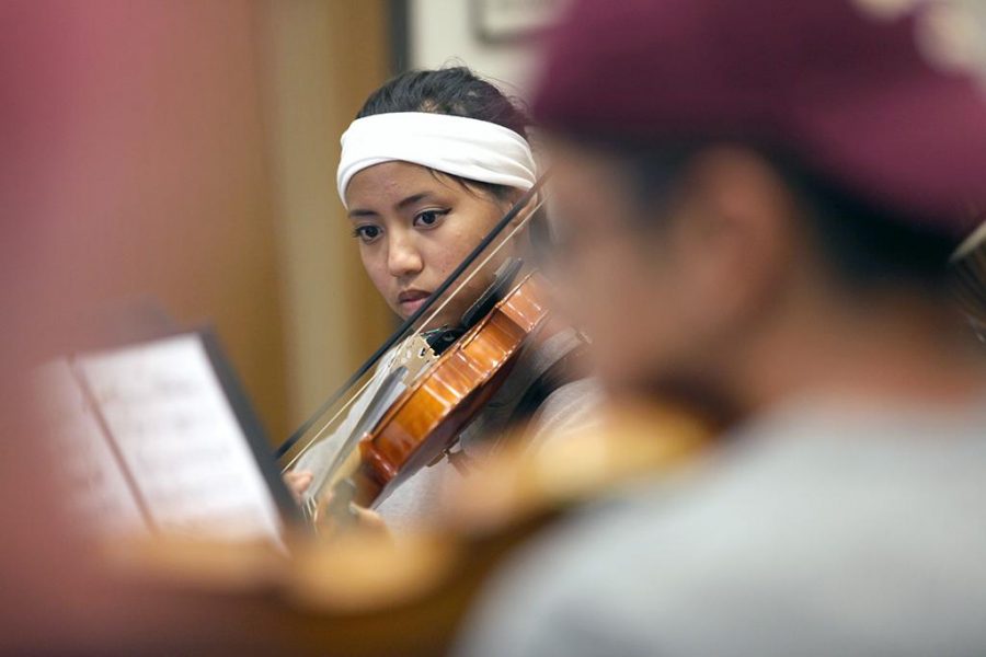 Christelle Billan, music performance and biology freshman, plays music on her violin during orchestra practice in the band hall, Oct. 13. Photo by Rachel Johnson
