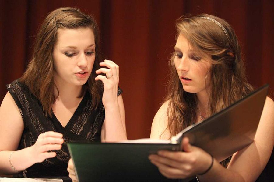Madison Tedder, vocal music education freshman, and Nicole Anderson, education junior, do vocal exercises and practice their music before the Midwestern Singers and University Orchestra performance held in Akin Auditorium, Nov. 10. Photo by Rachel Johnson