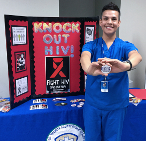 Jesse Velasquez, Wichita Falls Health Department technician, holds an HIV awareness button at the HIV testing booth outside Shawnee Theatre in the CSC on Feb. 12. Photo by Rutth Mercado