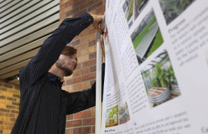 William Statham, mechanical enginering senior, adjusts his poster on aquaponics April 28. Photo by. Topher G. McGehee
