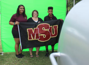 Sierra Jones, athletic training senior, Shana Hancock, mother of Sierra, and Devin Hancock, Sierra's brother, get their picture taken at one of the booths in the Quad put up for Family Day, Sept. 26, 2015. Photo by Rachel Johnson