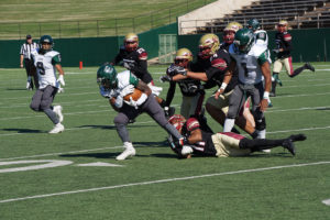 Marcus Wilkerson, mechanical engineering freshman, holds tightly to an Eastern New Mexico causing a group tackle on Sept. 12. Photo by Topher G. McGehee