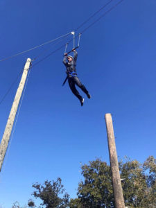 Management sophomore Greta Lazzarotto leaps for the bar during the ropes course. Photo by Zack Santagate
