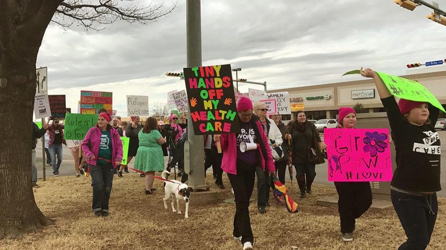Women, men, children and puppies reach the end of the two mile Womens March on The Falls as they reach the Fidelity Bank building. Photo By Caleb Martin