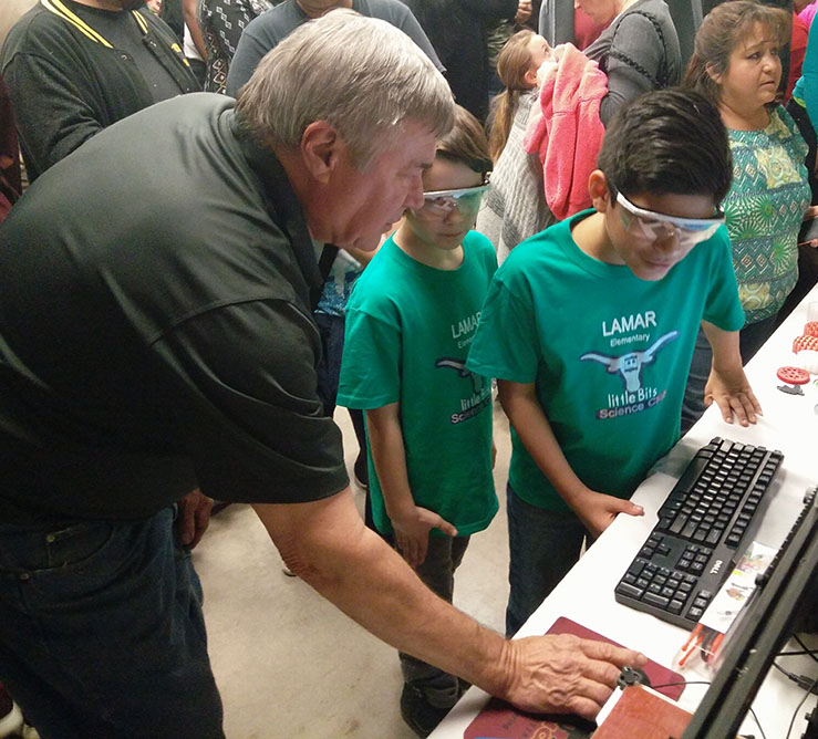 Frank Bohuslav, engineering machinist technician, shows two students from Lamar Elementary how a 3D printer works at MacGyver Science Fair on Jan. 26. Photo by Timothy Jones