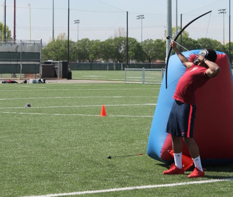 Back arched, Selvian Peters shoots arrow while playing Archery Tag.