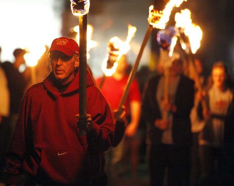 Bill Maskill, head football coach, walks through the crowd with a tiki torch to begin the homecoming bonfire, Thursday, Oct. 19, 2017. Photo by Francisco Martinez