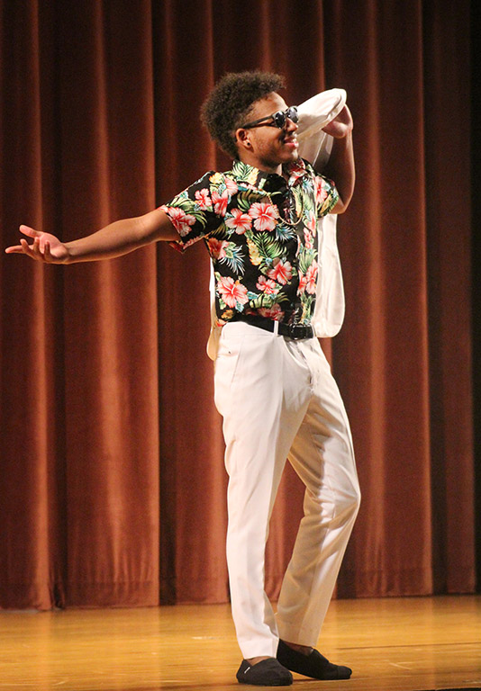 Trevon Charles, biology sophomore, throws his suit jacket over his shoulder while he walks around the stage showing off his outfit during the evening wear portion of the 2017 Mr. and Miss Caribfest Pageant held in Akin Auditorium Sept. 28. Photo by Marissa Daley