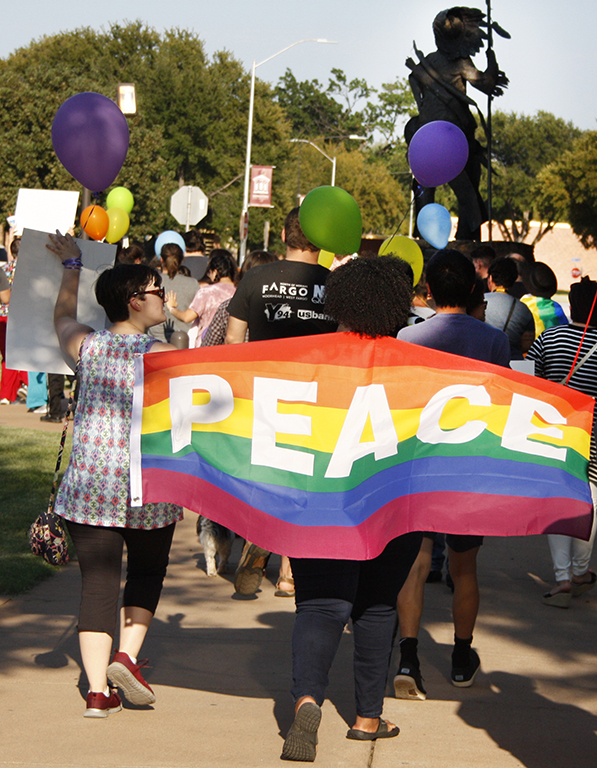 Shaniece Dutch , sociology senior, holds up a pride flag with the word peace on it during the march at the resist hate rally held at the Sunwatcher Plaza on Sep. 1. Photo by Justin Marquart