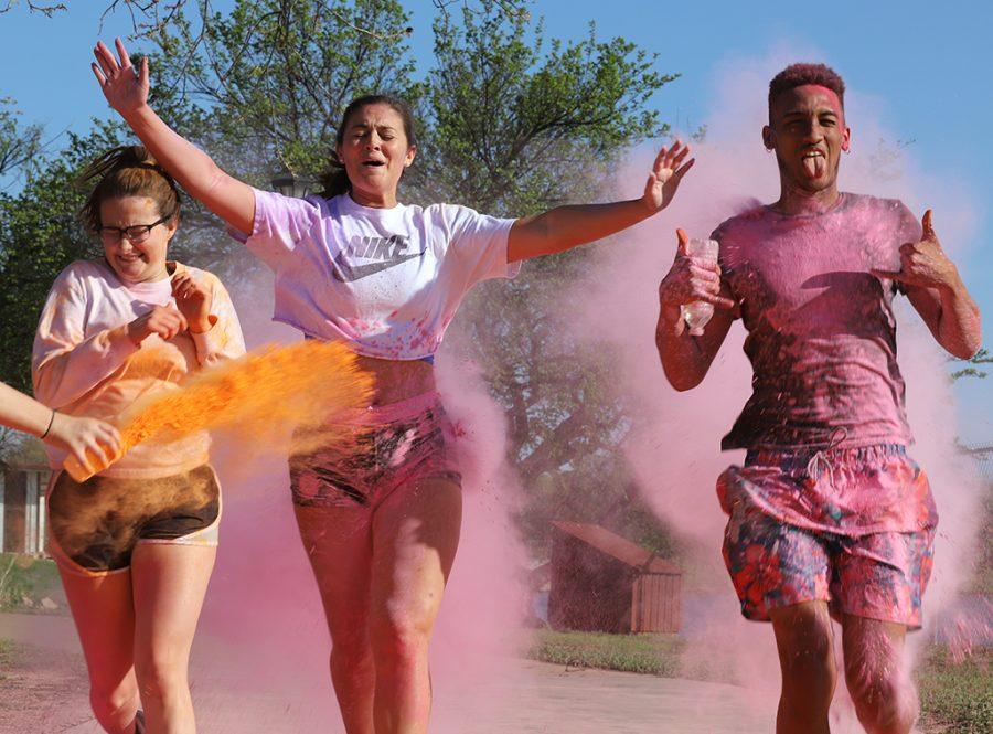 Madelyn Williams, sports and leisure sophomroe, Alex Blake, finance senior, and Zach Alvarez, excercise physiology runs through the colored chalk during the 5Kolor Run at Sikes Lake Trail on April 18, 2018. Photo by Sarah Graves