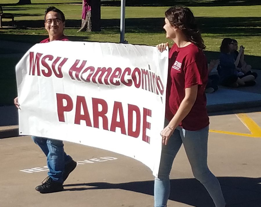 Taylor McCreary management senior and Jose Zambrano Graphic Design sophomore hold the Homecoming Parade banner on October 27, 2018. Phone Photo by Stephen Gomez