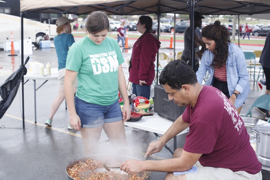 Lydia Acuña, freshman exercise physiology major, helps her dad, Poló, make discada for the Baptist Student Ministry booth at the tailgate on Oct. 6 2018 at Memorial StadiumPhoto by Jared Bruner