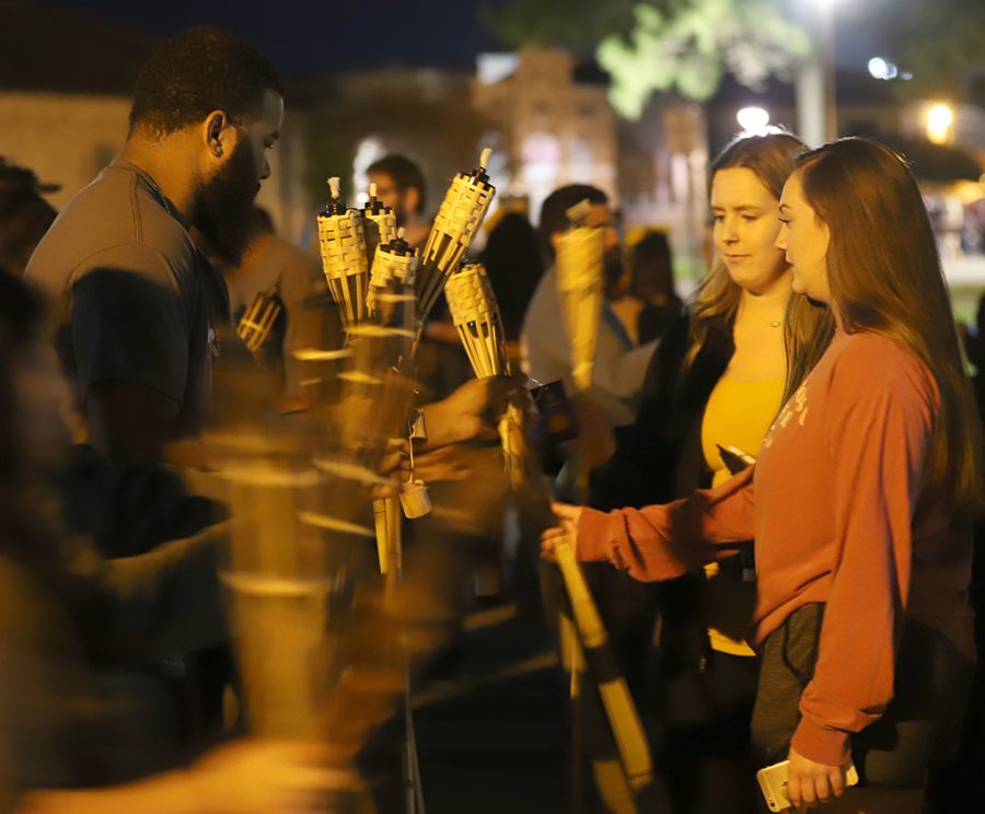 UPB volunteers pass out torches to students before torchlight parade.