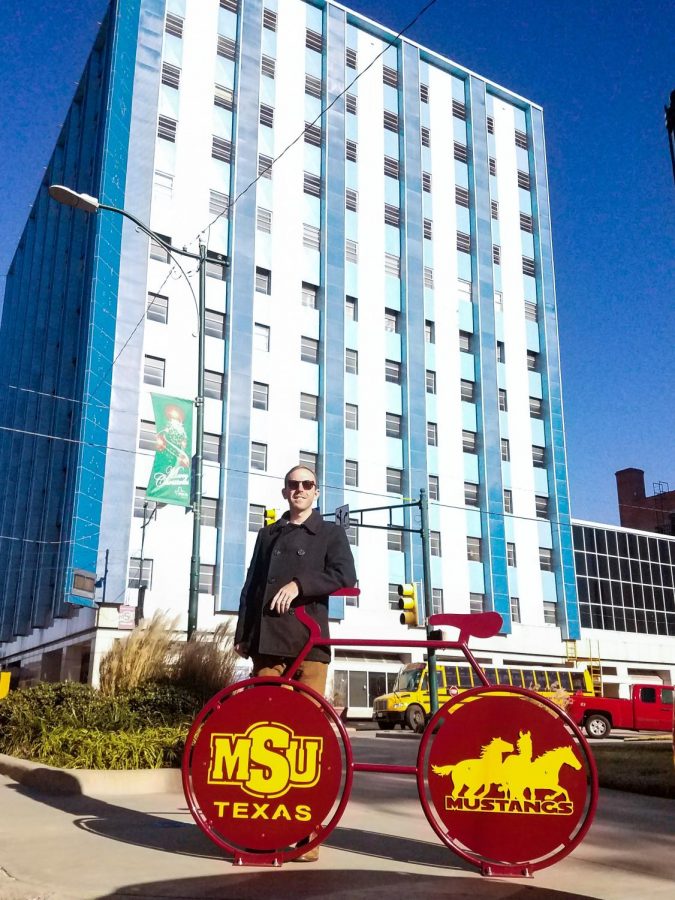 Charlie Zamastil, cycling team director, shows off the new MSU bike rack downtown in front of Big Blue.