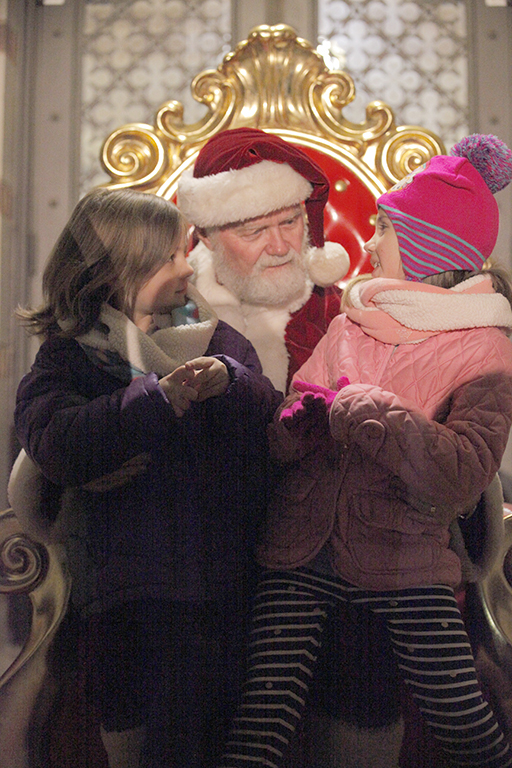 Elizabeth and Sarah Davidson tell Santa Claus what they would like for Christmas at the Fantasy of Lights opening ceremony.
