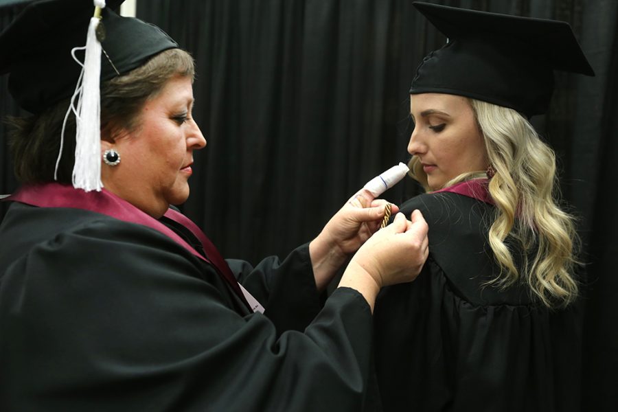Cathy Lynn Quintero-McElroy adds honor cords to Claire Fowler at Midwestern State University graduation Dec. 15, 2018. Quintero-McElroy said she just got out of the hospital after a splinter in her finger that she got while putting up the Christmas tree got infected. Photo by Bradley Wilson