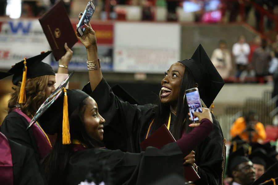 Rachel Nnami and Claudette Muna, both of whom received Presidents Medals and had 4.0 GPAs, shoot video during the singing of the alma mater at Midwestern State University graduation Dec. 15, 2018. Photo by Bradley Wilson